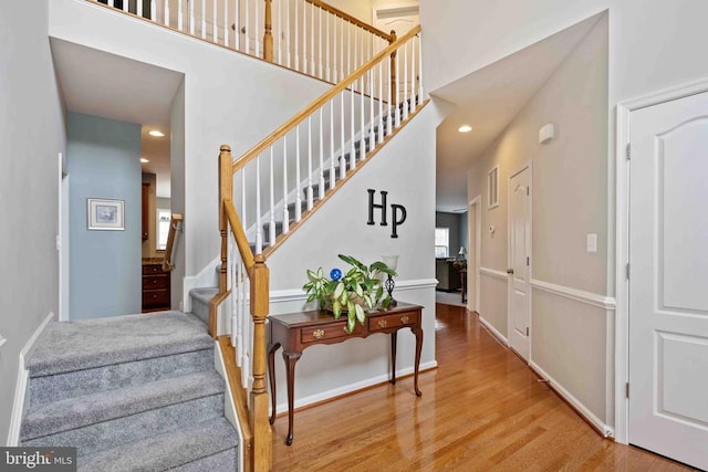 stairs with a towering ceiling, baseboards, and wood finished floors