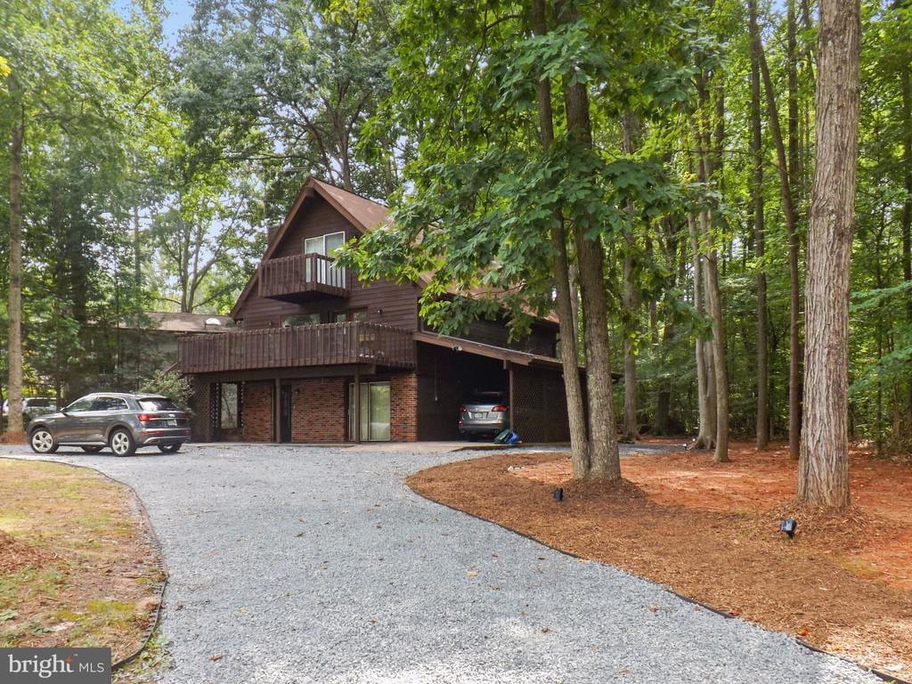 rustic home featuring an attached carport and gravel driveway