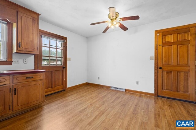 kitchen with light wood-type flooring, baseboards, ceiling fan, and brown cabinets