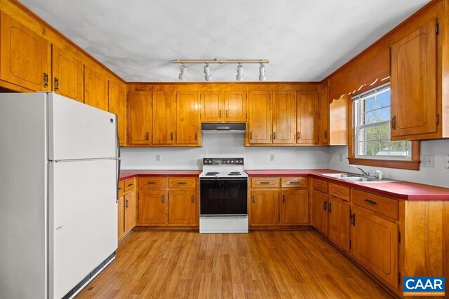 kitchen featuring freestanding refrigerator, under cabinet range hood, electric stove, and brown cabinets