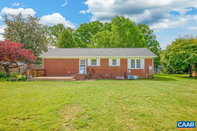 back of property featuring fence, brick siding, a deck, entry steps, and a yard
