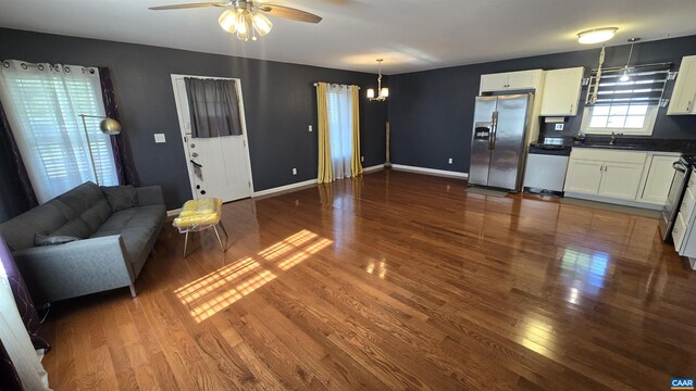 unfurnished living room with ceiling fan with notable chandelier, dark hardwood / wood-style floors, and sink