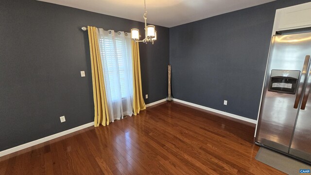 unfurnished room with dark hardwood / wood-style flooring and an inviting chandelier