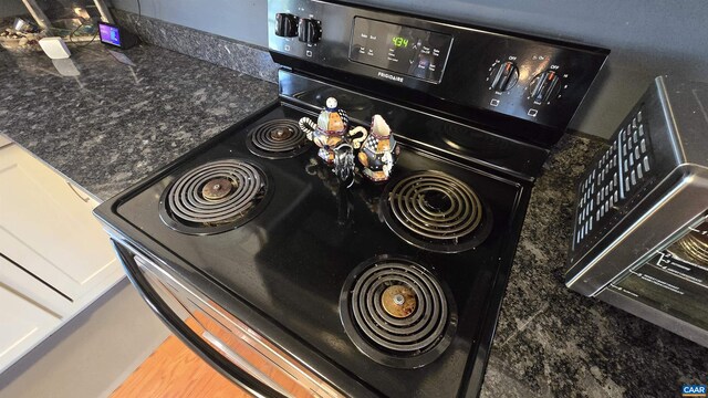 interior details with black range with electric cooktop and dark stone counters