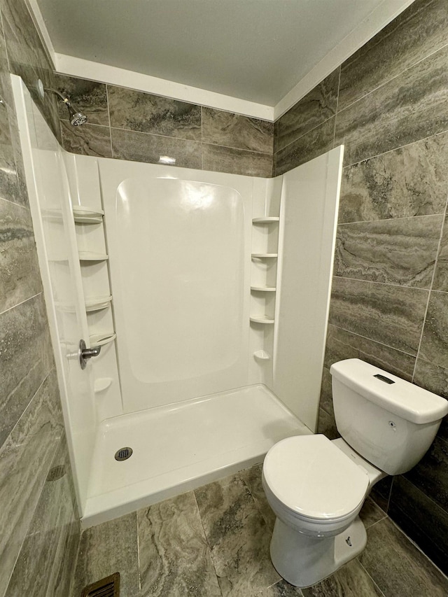 bathroom with tile walls, toilet, and walk in shower