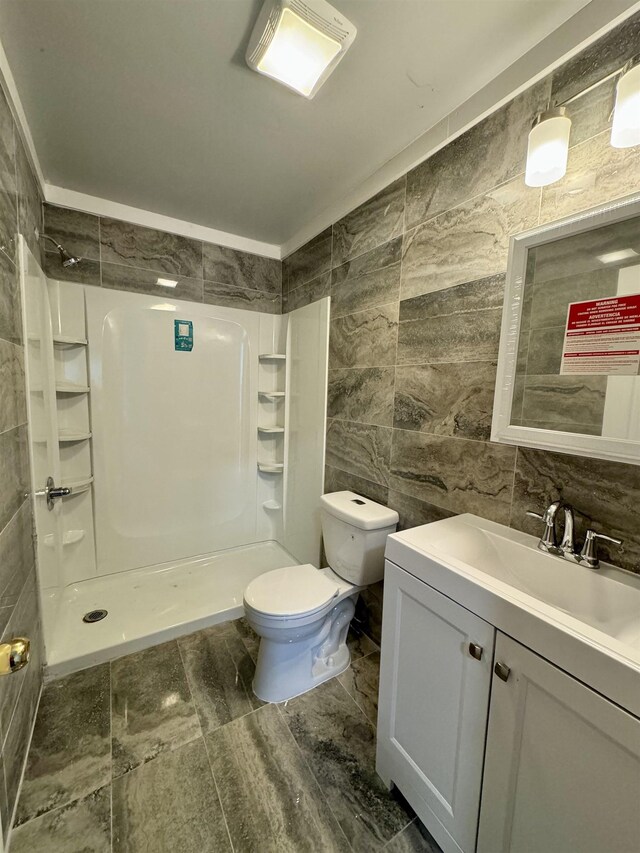 bathroom with vanity, toilet, tile walls, and a shower