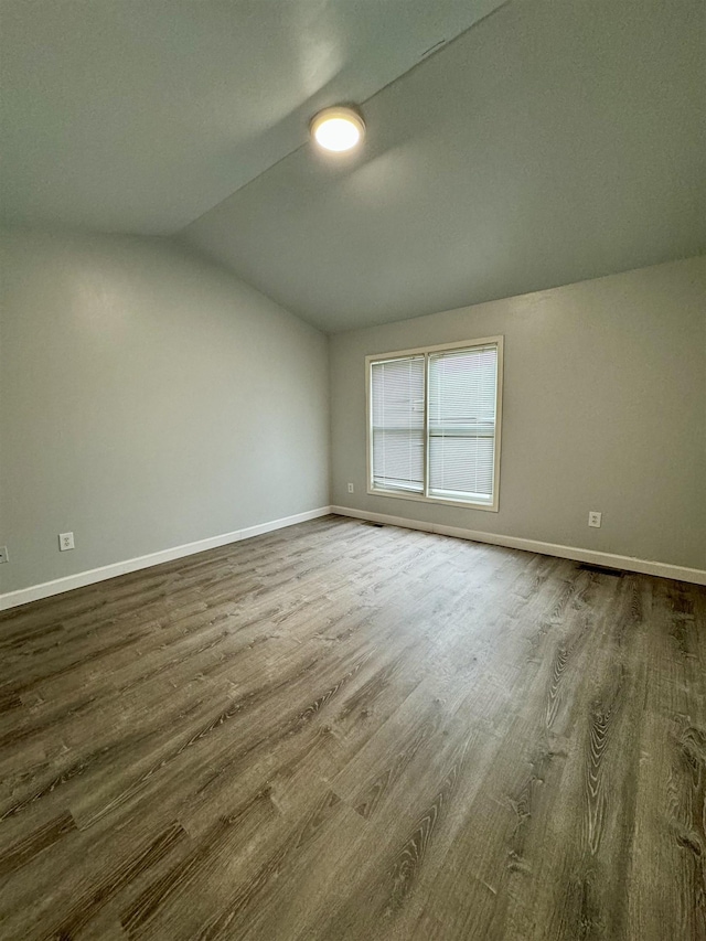 spare room with wood-type flooring and lofted ceiling