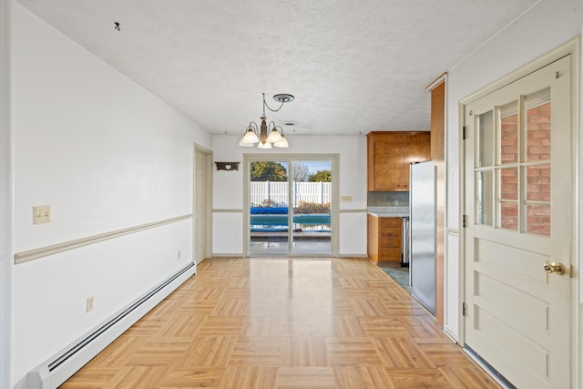 unfurnished dining area with an inviting chandelier, a baseboard radiator, a textured ceiling, and light parquet floors