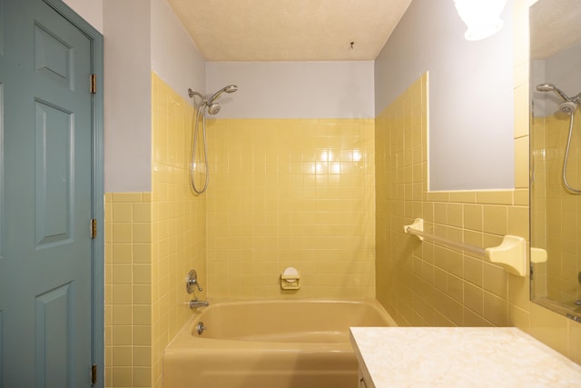 bathroom with tiled shower / bath, vanity, and tile walls