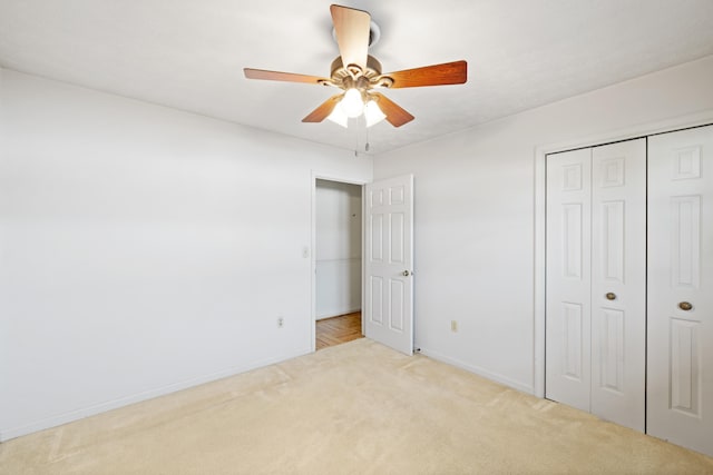 unfurnished bedroom featuring ceiling fan, a closet, and light carpet