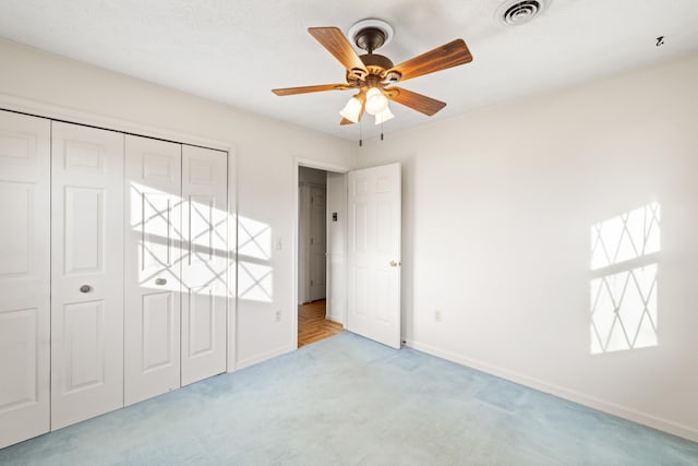 unfurnished bedroom featuring ceiling fan, a closet, and light carpet