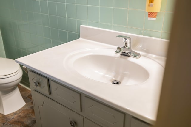 bathroom with tile walls, vanity, and toilet