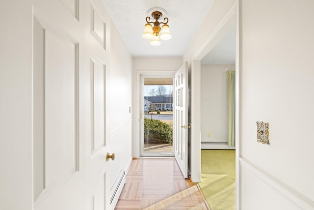 doorway to outside featuring light parquet floors, a baseboard radiator, and a textured ceiling