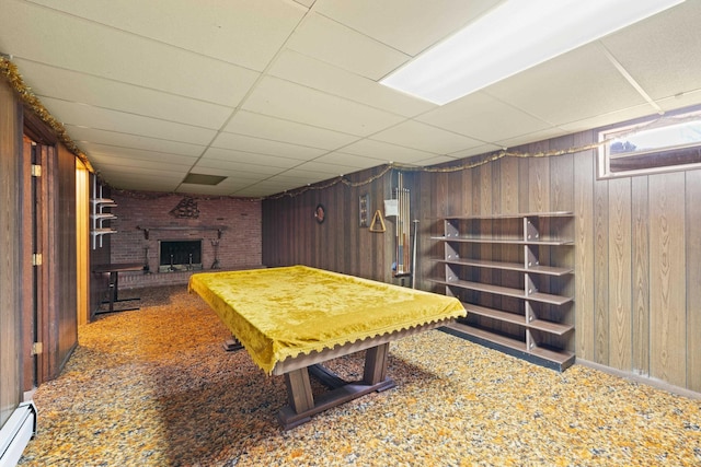 game room featuring a paneled ceiling, a fireplace, wood walls, carpet, and baseboard heating