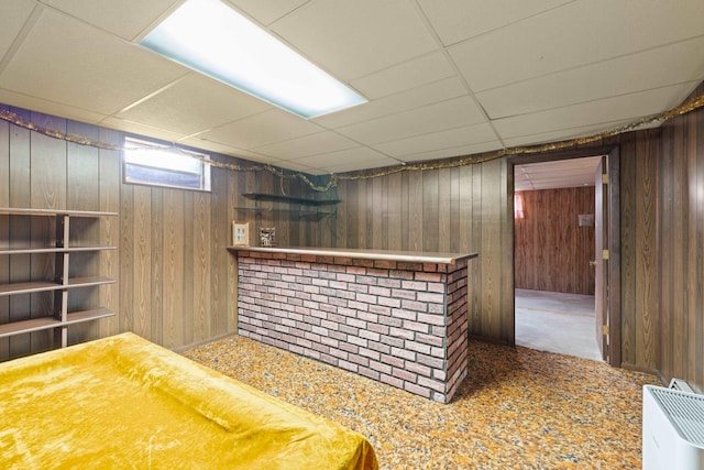 bar featuring a drop ceiling and wood walls