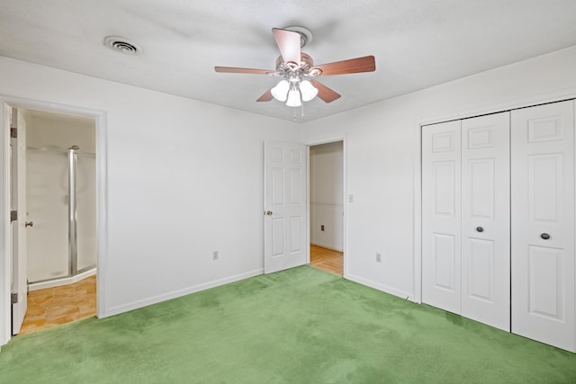 unfurnished bedroom with ensuite bath, carpet floors, a closet, and ceiling fan