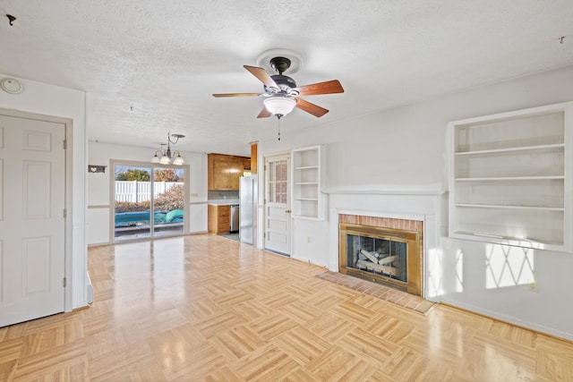 unfurnished living room with ceiling fan, light parquet flooring, a fireplace, and a textured ceiling