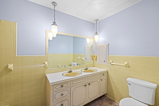 bathroom featuring vanity, tile walls, a textured ceiling, and toilet