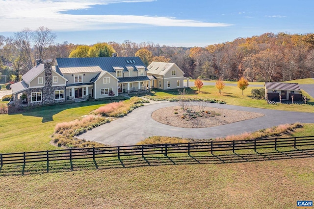 view of front of property featuring curved driveway, metal roof, a standing seam roof, fence, and a front lawn