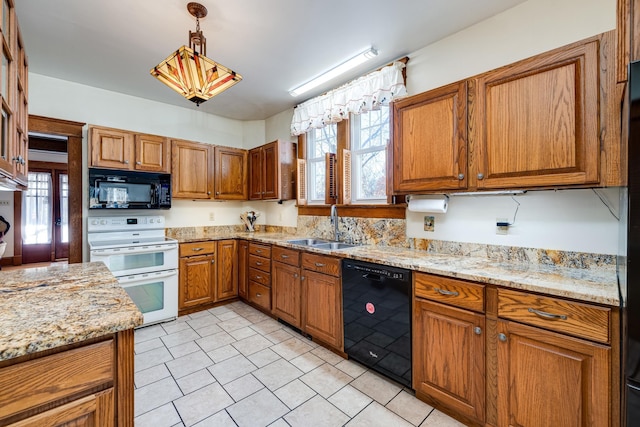 kitchen featuring decorative light fixtures, light stone countertops, sink, and black appliances