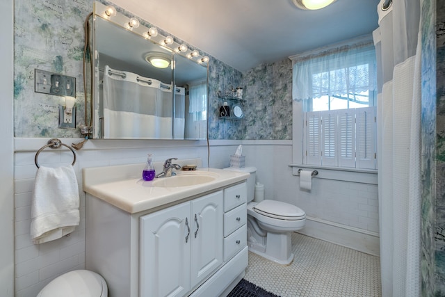 bathroom with tile patterned floors, toilet, vanity, and tile walls