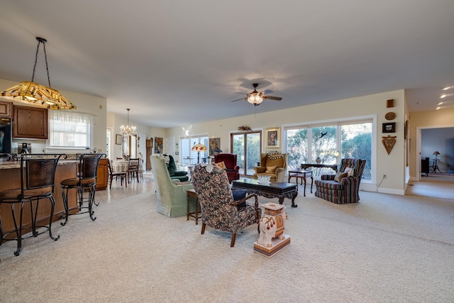 carpeted living room with ceiling fan with notable chandelier