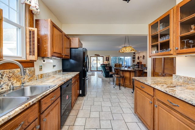 kitchen featuring sink, decorative light fixtures, black appliances, and light stone countertops