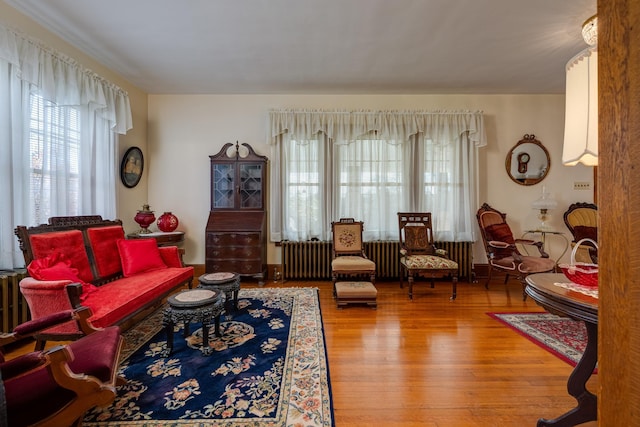 living area with hardwood / wood-style floors and radiator heating unit