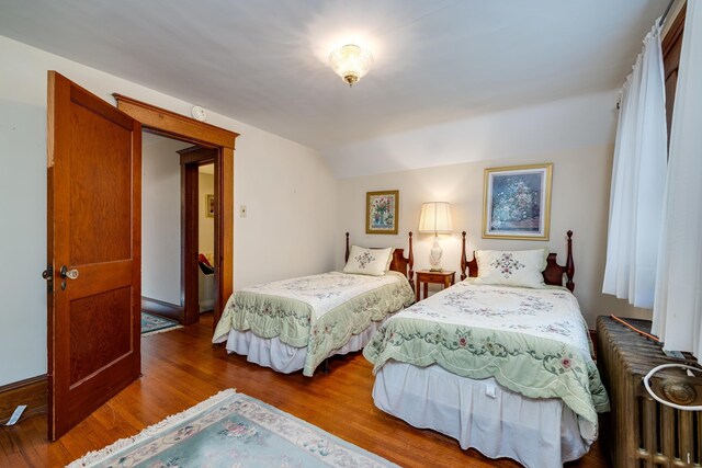 bedroom with lofted ceiling, hardwood / wood-style floors, and radiator