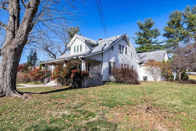 view of side of home featuring a porch and a lawn