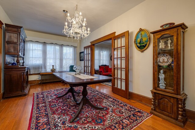 office area with an inviting chandelier, radiator, french doors, and light wood-type flooring