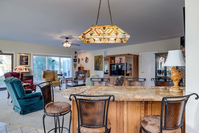 kitchen with light stone counters and ceiling fan