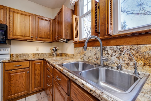 kitchen featuring light stone counters, sink, white electric range, and light tile patterned flooring