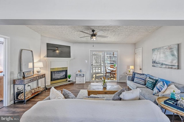 living area featuring dark wood-type flooring, a glass covered fireplace, and a textured ceiling