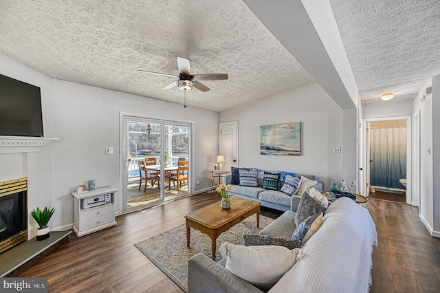 living area with dark wood-style floors, a textured ceiling, a glass covered fireplace, and baseboards