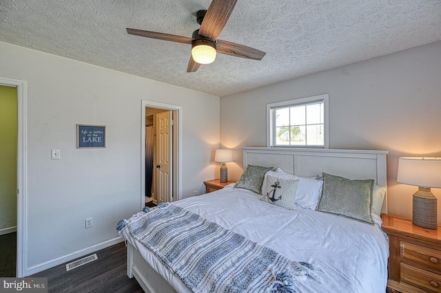 bedroom featuring ceiling fan, dark wood-type flooring, and a textured ceiling