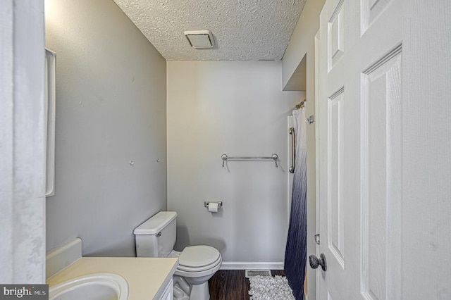 full bath with visible vents, toilet, wood finished floors, a textured ceiling, and vanity