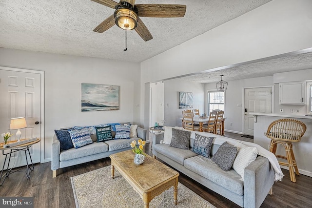 living area featuring a textured ceiling, dark wood finished floors, and a ceiling fan