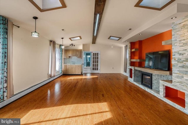 unfurnished living room with lofted ceiling with beams, light wood-type flooring, a fireplace, and baseboard heating