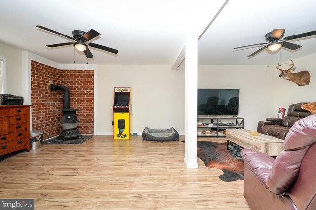 living room with ceiling fan, a wood stove, and light wood-type flooring