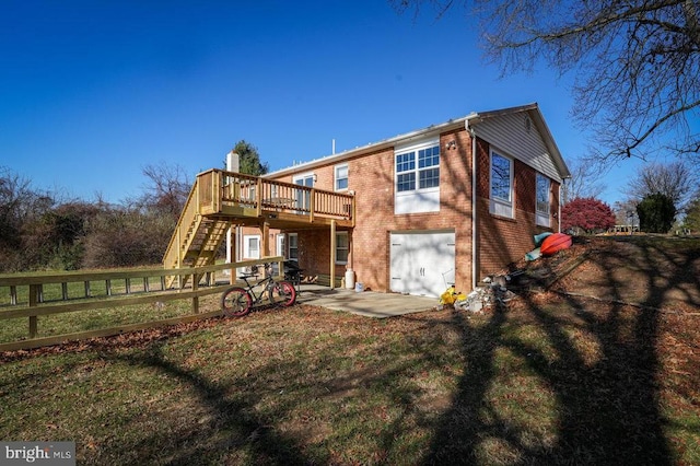 rear view of property featuring a garage, a lawn, a deck, and a patio area