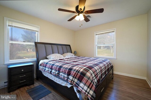 bedroom featuring ceiling fan, a baseboard heating unit, and dark hardwood / wood-style flooring