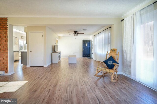 unfurnished room with a textured ceiling, ornamental molding, ceiling fan, and light wood-type flooring