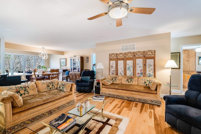 living room featuring ceiling fan with notable chandelier and light hardwood / wood-style floors