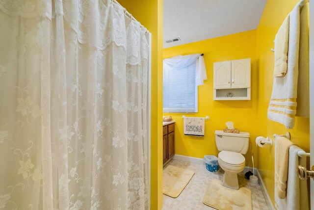 bathroom with vanity, tile patterned floors, toilet, and a textured ceiling