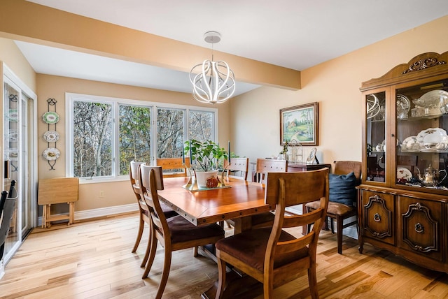 dining area featuring beam ceiling, an inviting chandelier, and light wood-type flooring