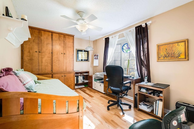 bedroom with ceiling fan, a textured ceiling, and light wood-type flooring