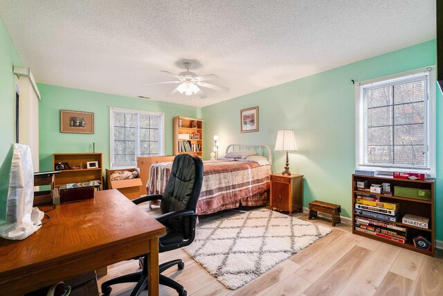 bedroom featuring ceiling fan, light hardwood / wood-style floors, and a textured ceiling