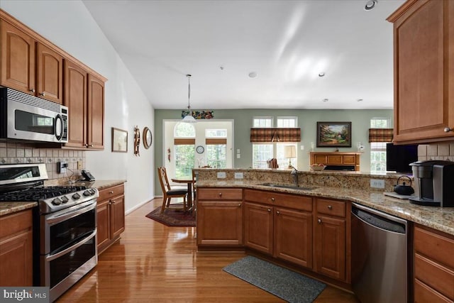 kitchen featuring stainless steel appliances, tasteful backsplash, a sink, and a peninsula