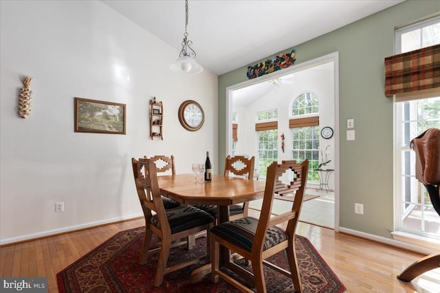 dining room with baseboards, vaulted ceiling, plenty of natural light, and light wood-style flooring